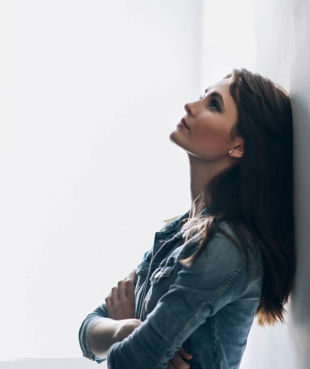 woman thinking deeply leans against a wall