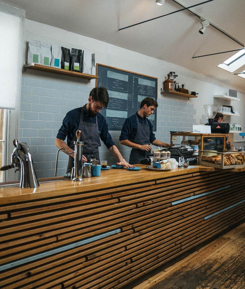 two baristas working behind coffee shop counter