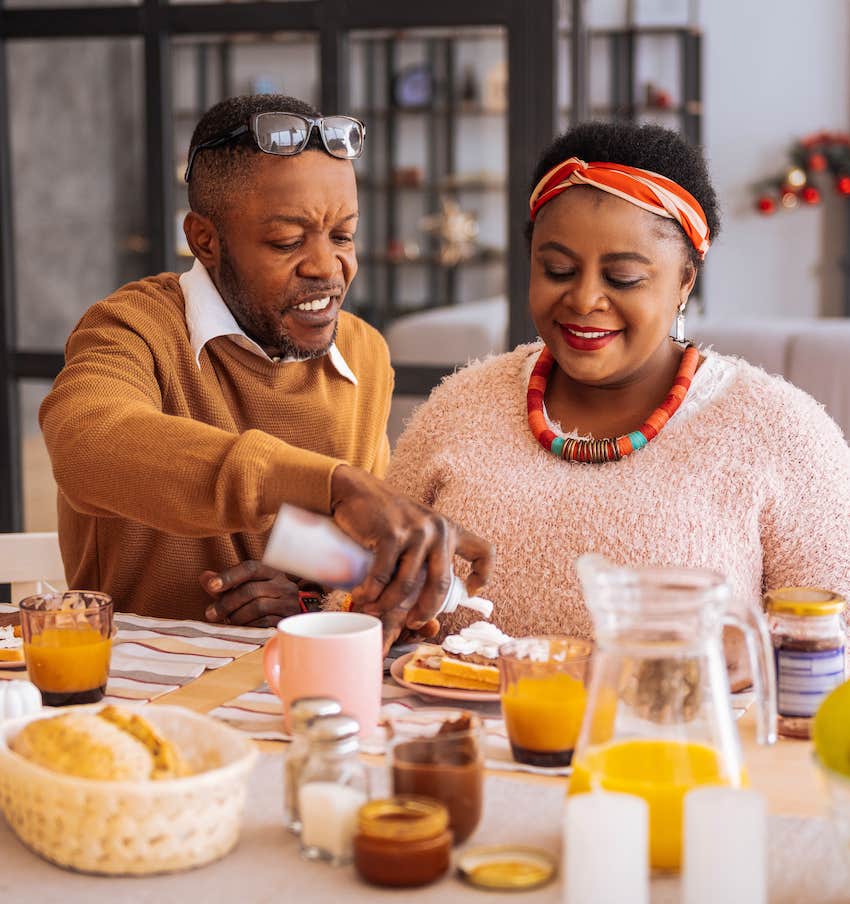 joyful couple sitting at the table while having breakfast together