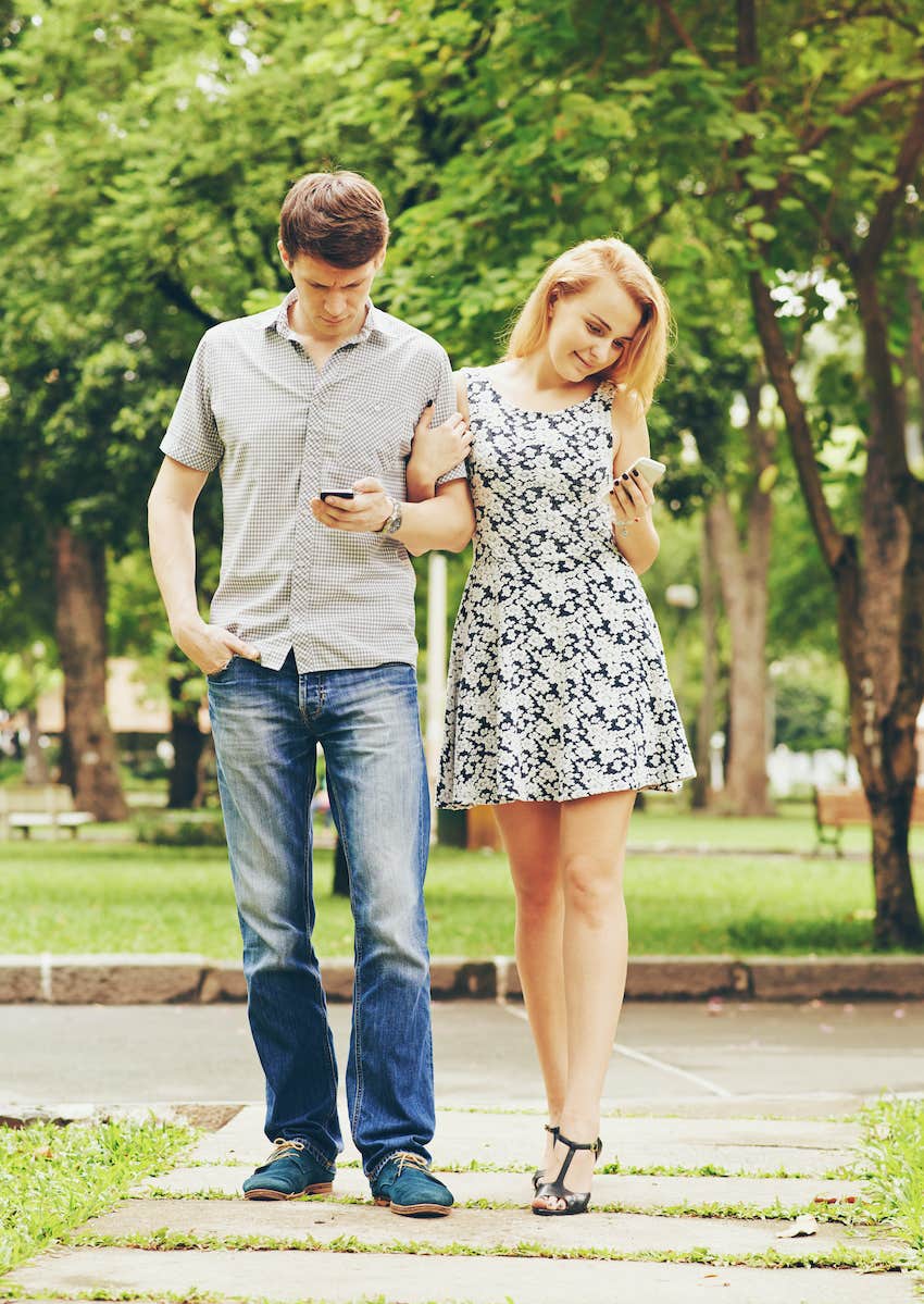 couple texting and walking