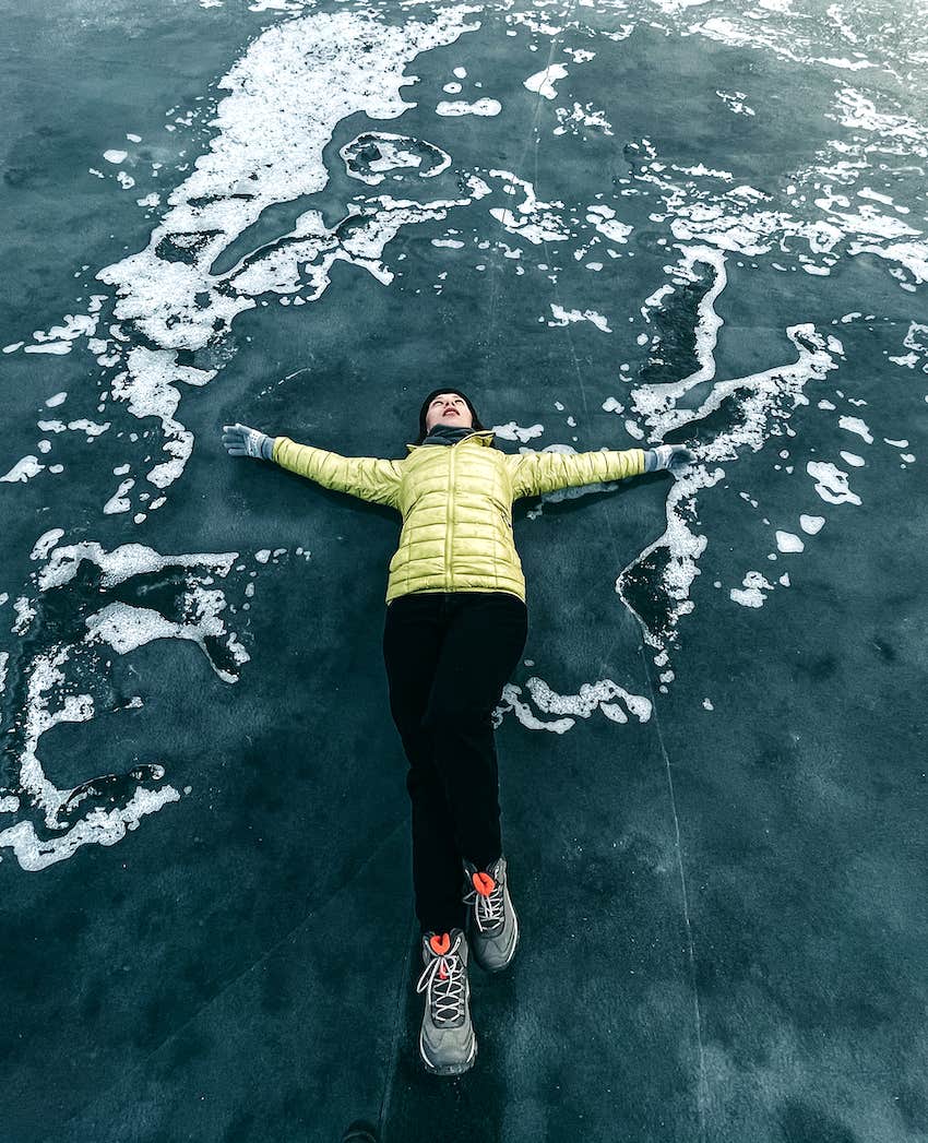 Relaxing on a blue ice-frozen lake with snow and cracks in winter