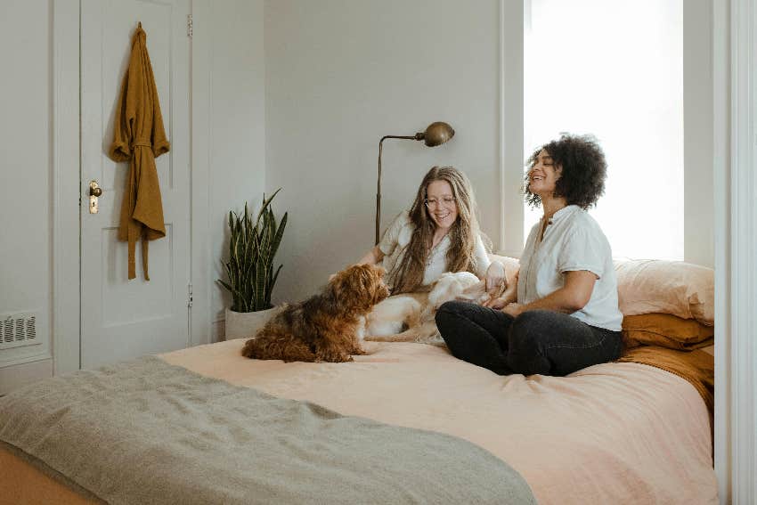 two girls hanging out in a bedroom with a dog