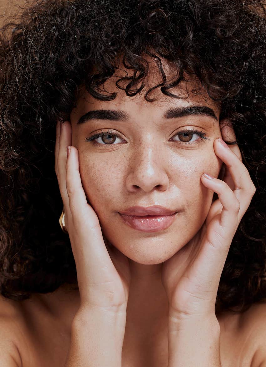 woman touching cheeks for self love and wellness.