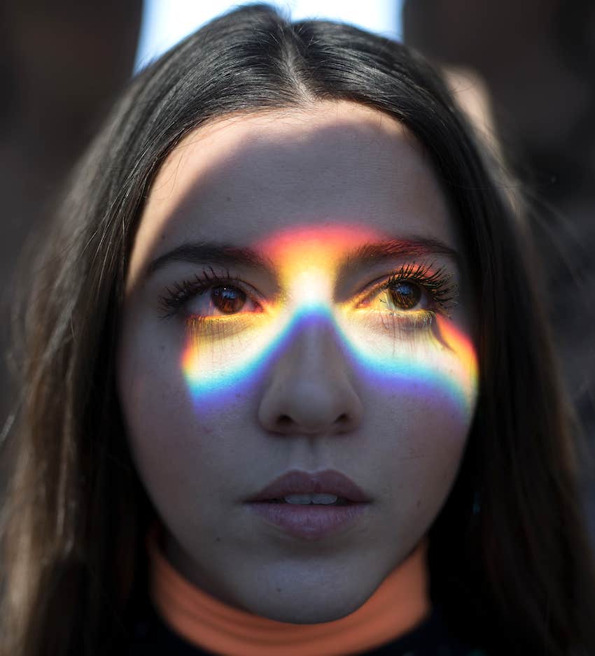 a rainbow of light dances across her face