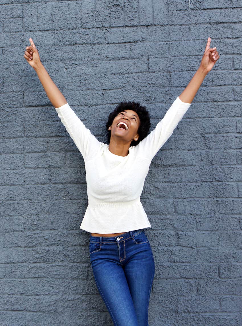 cheerful woman with hands raised pointing up