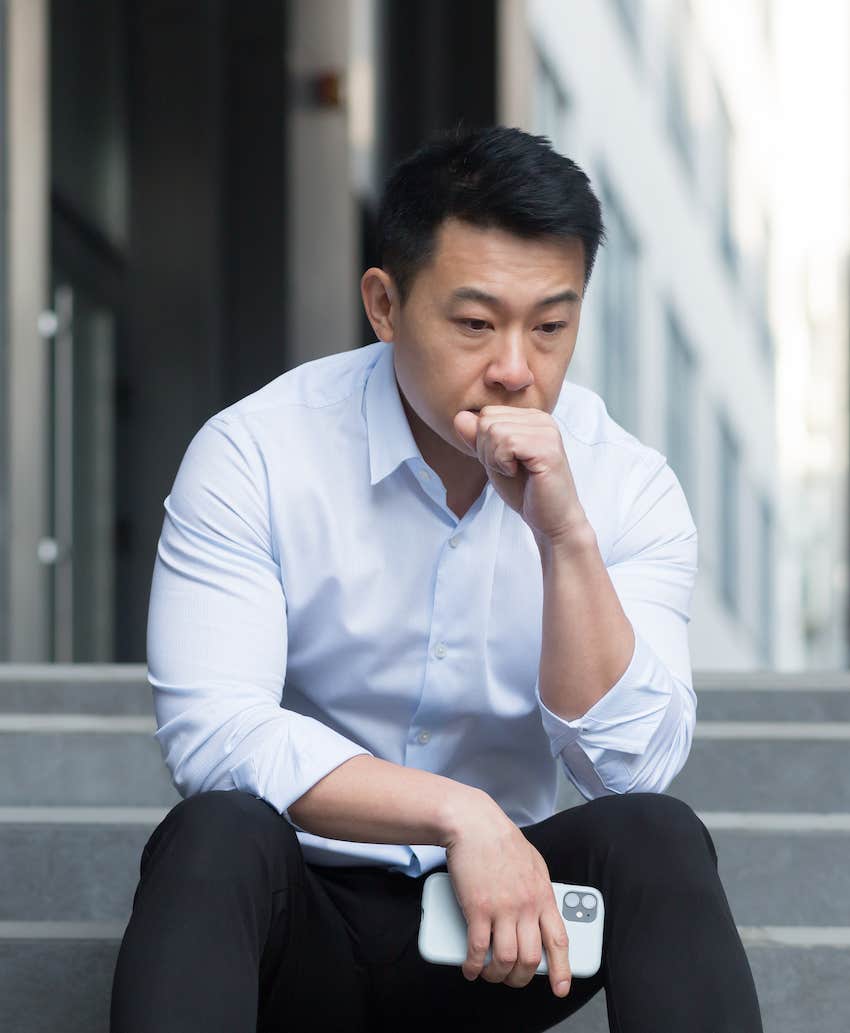 upset man sits on stairs outside