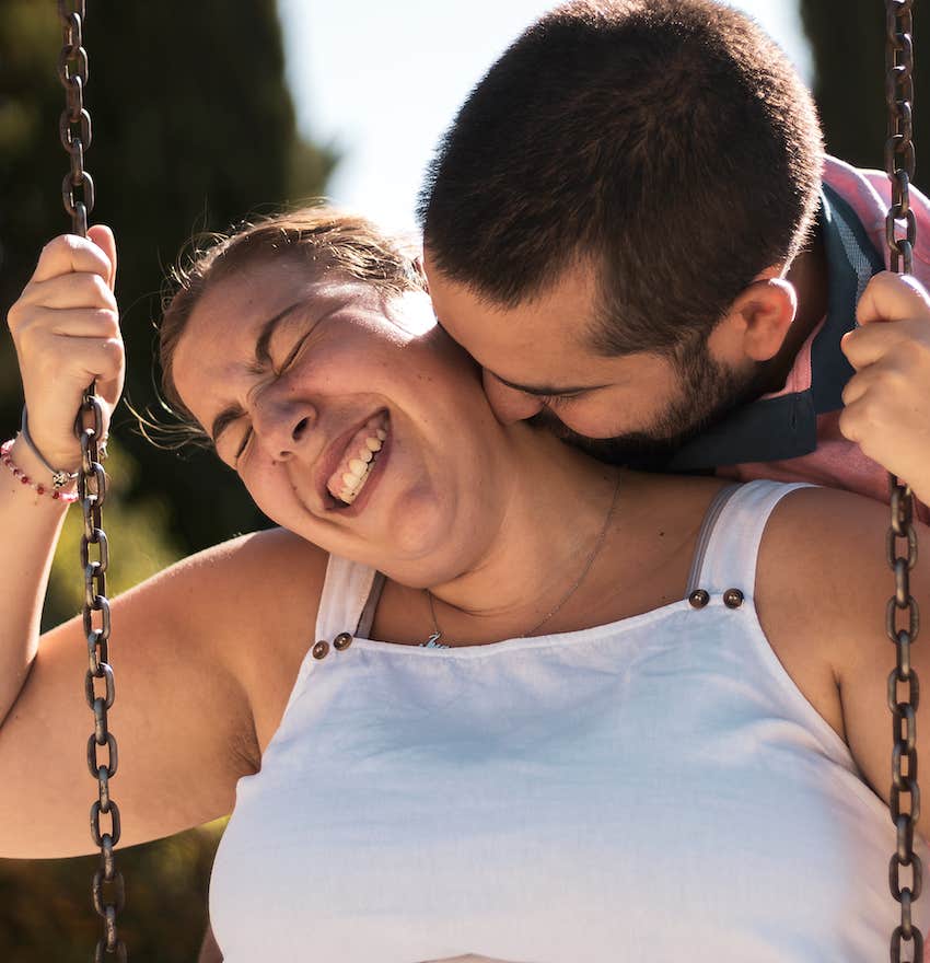 fun couple swinging on a swing in a park