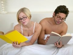 Couple wearing glasses and reading in bed