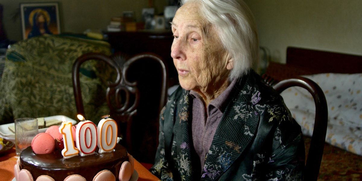how to live a long life 100-year-old woman blowing birthday candle.