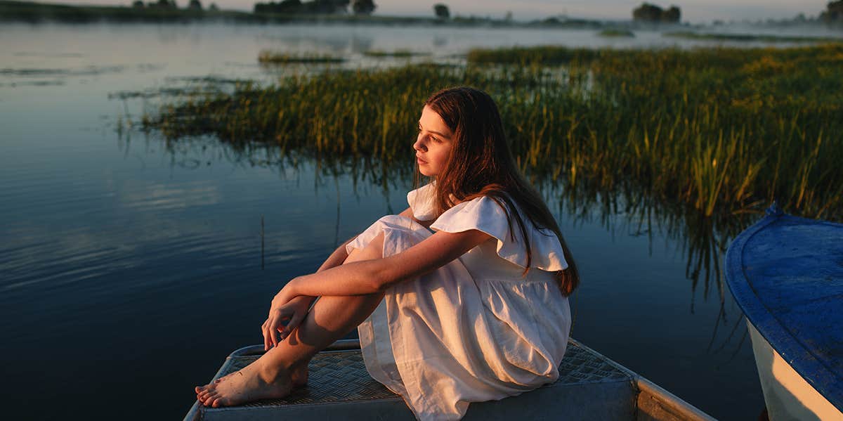 girl sitting alone near water