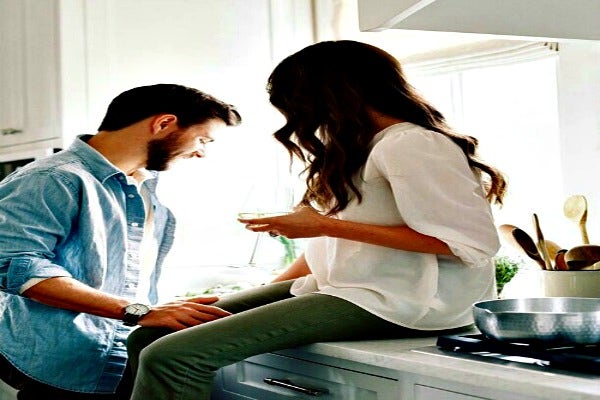 Woman drinks wine while man cooks. Woman drinks wine while man cooks.