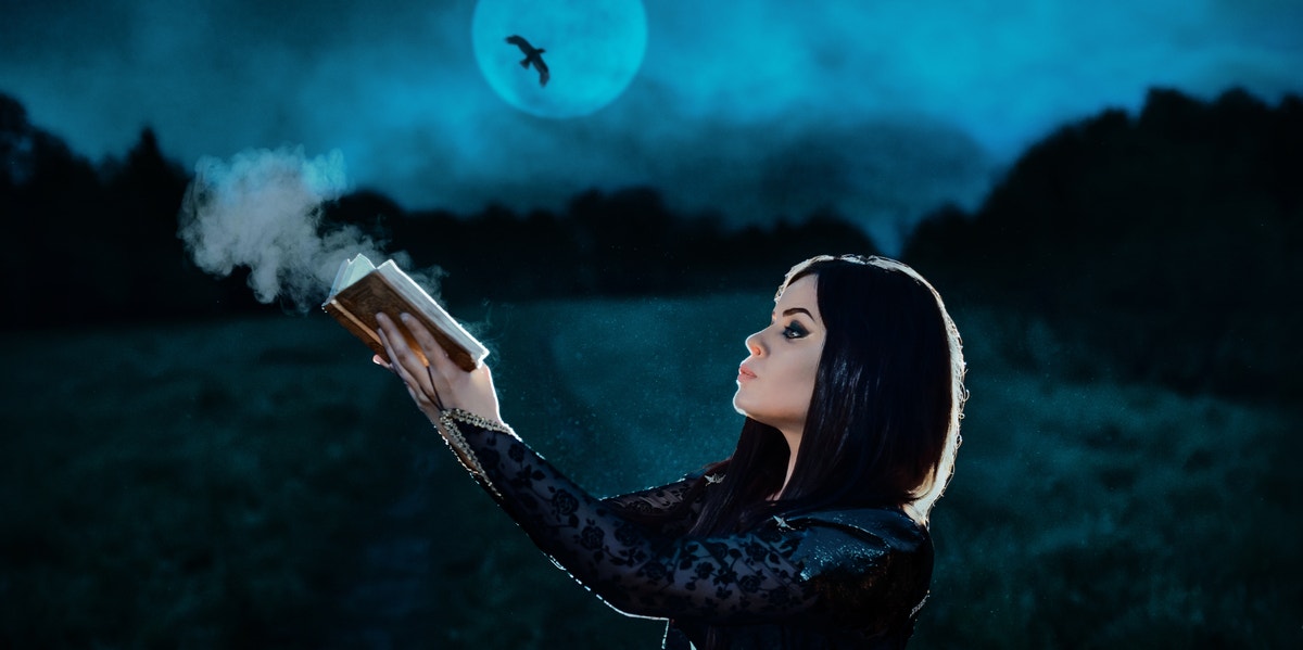 woman holding book under moon