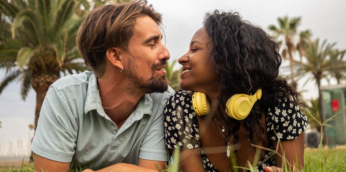 10 Ways His Body Doesn't Lie (That Reveals He's Super Into You) man and woman laying on blanket outside