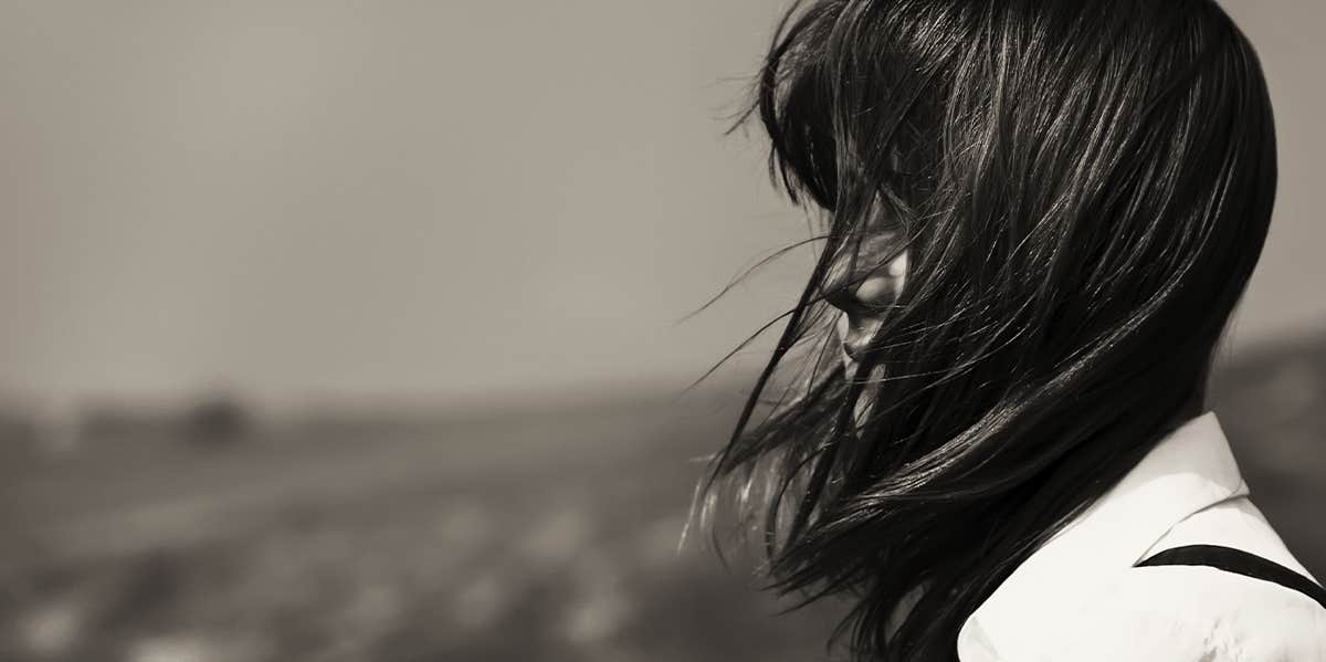 lone woman with hair blowing over her face