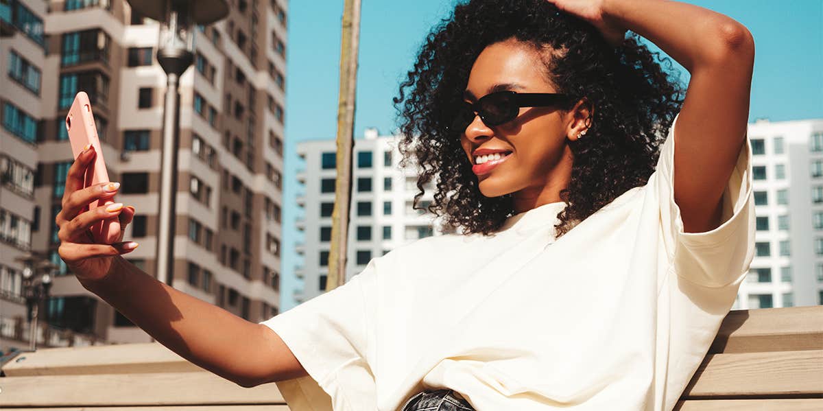 woman taking selfie on bench outside