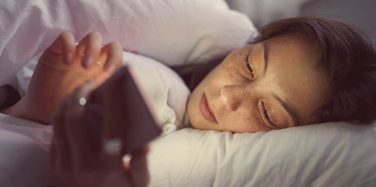 woman looking at phone in bed