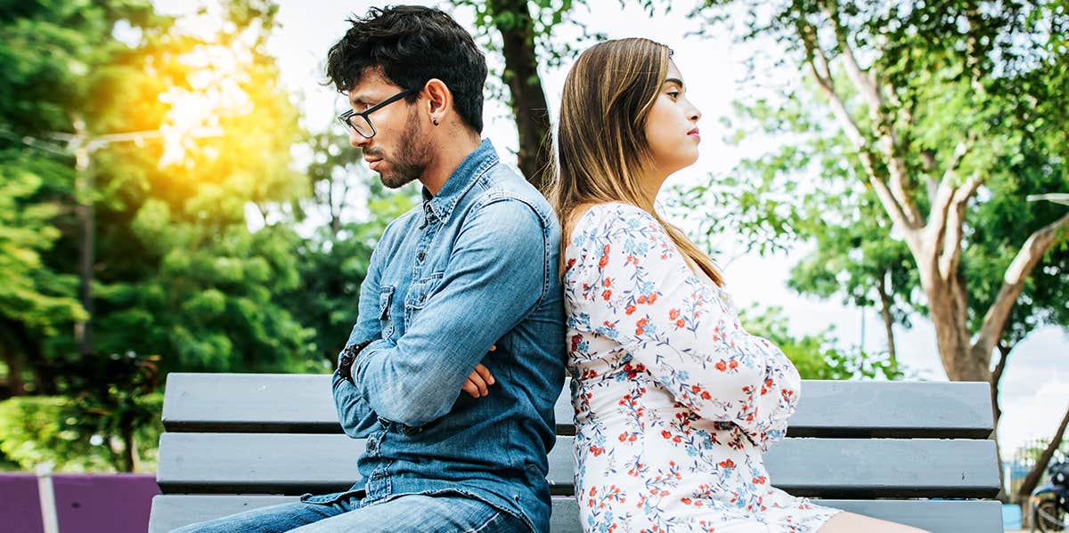 couple sitting back to back on bench