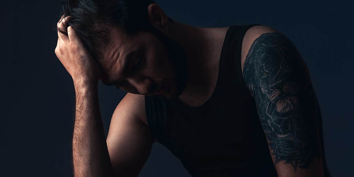 10 Traits Of "Undateable" Men That Are Actually Very Attractive man sitting in dark room with hand on face