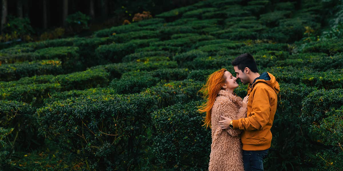 man and woman kissing in forest