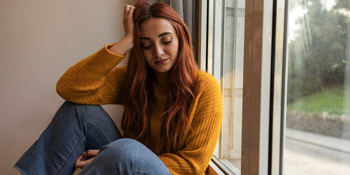 girl sitting alone at home near window