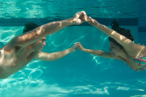 couple holding hands under water