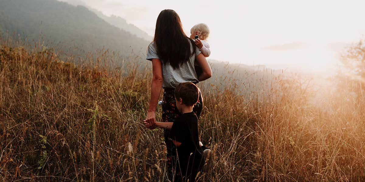 mother walking in field with two children