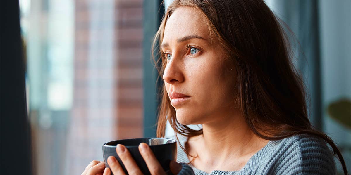 lonely girl standing by window