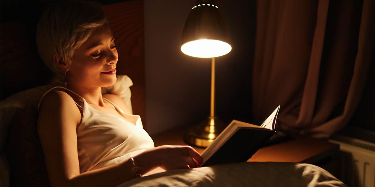 woman reading book in bed at night