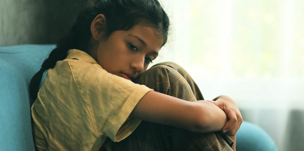 young girl sitting alone on couch