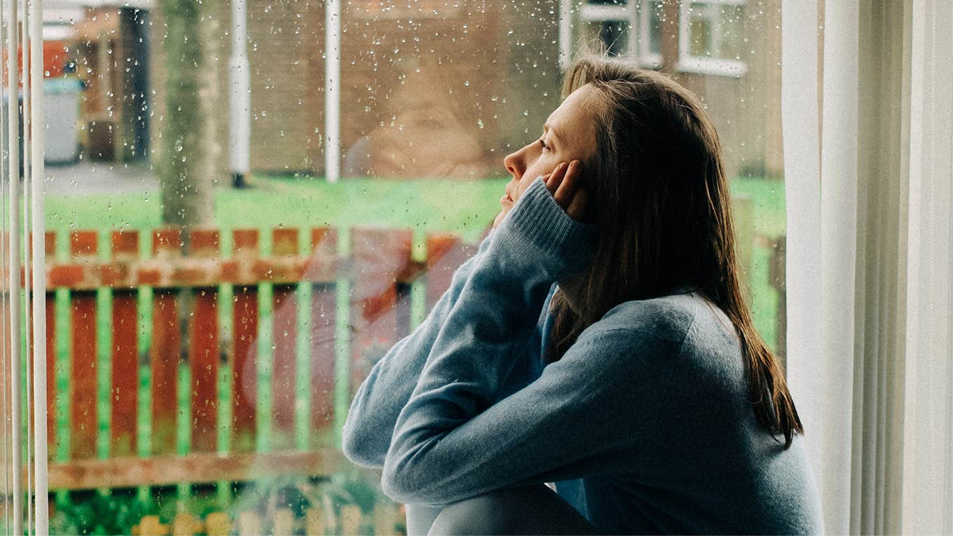 depressed woman sitting near window