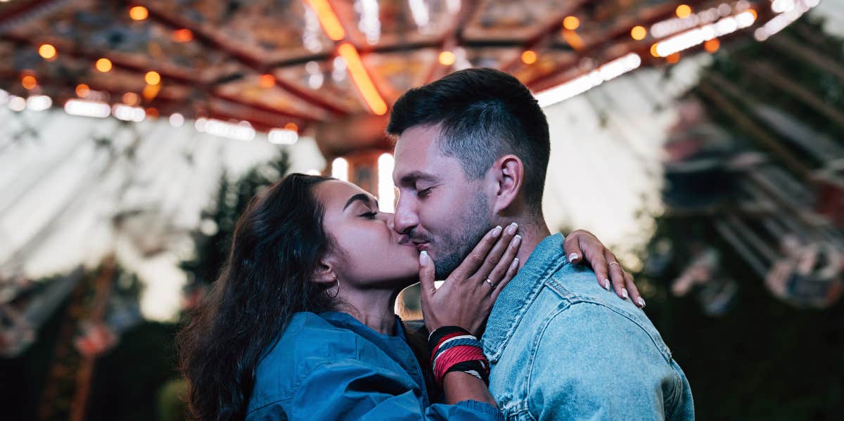 couple kissing in front of carousel 