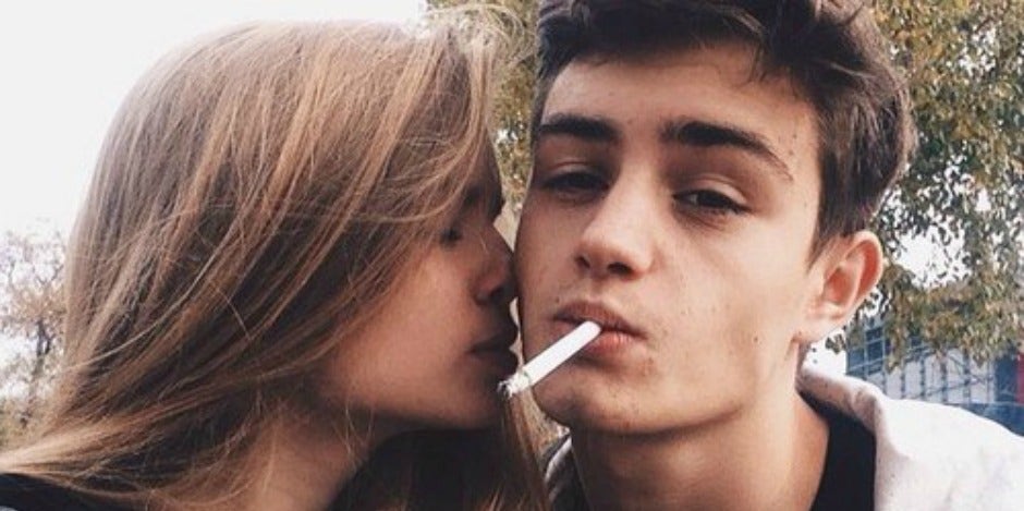 Guy smoking, girl kissing him