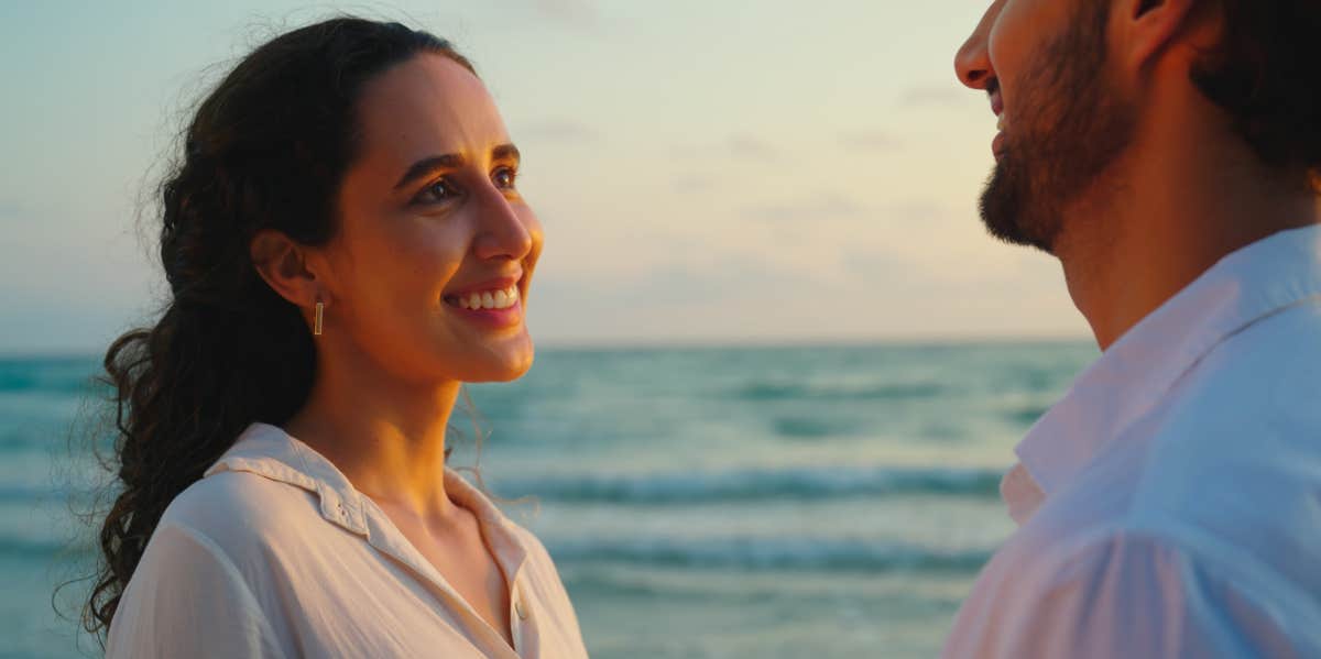 woman looking at man by the ocean