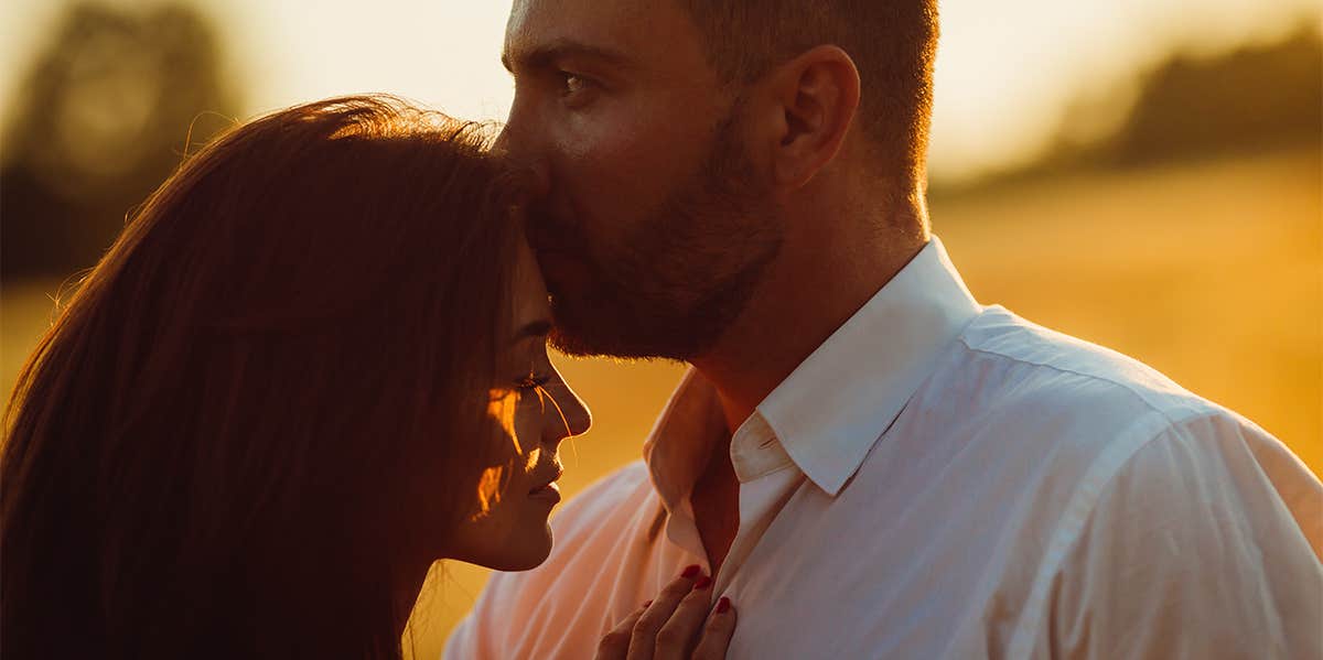 man kissing woman's head