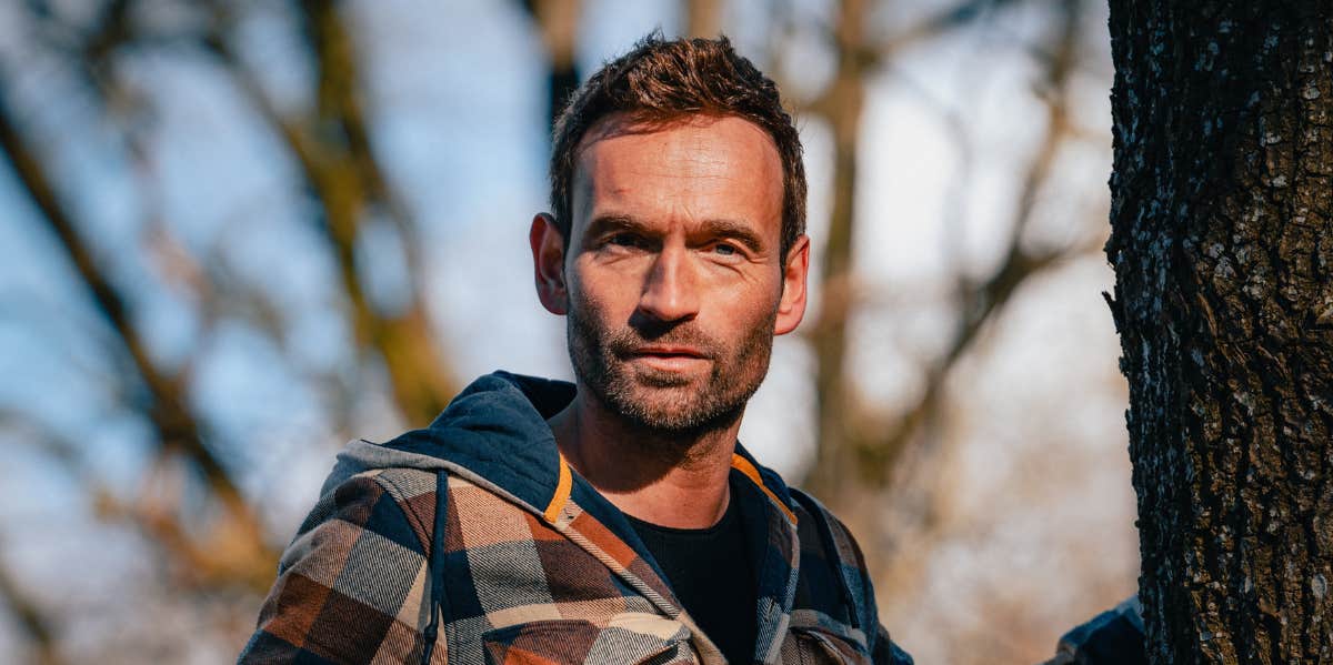 attractive man standing by tree