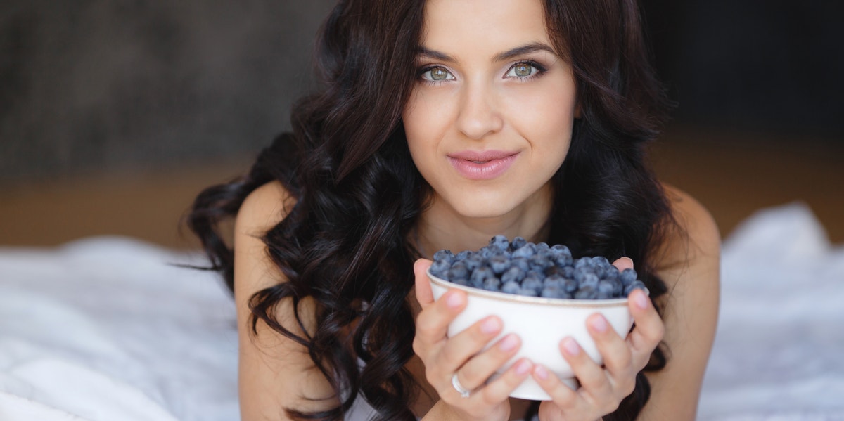 15 Best Brain-Boosting Foods You Should Be Eating Every Single Day woman with blueberries