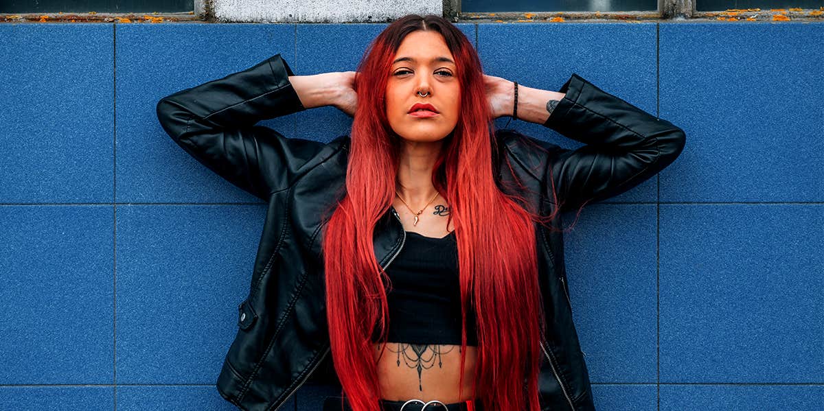 woman with red hair posing in front of blue wall