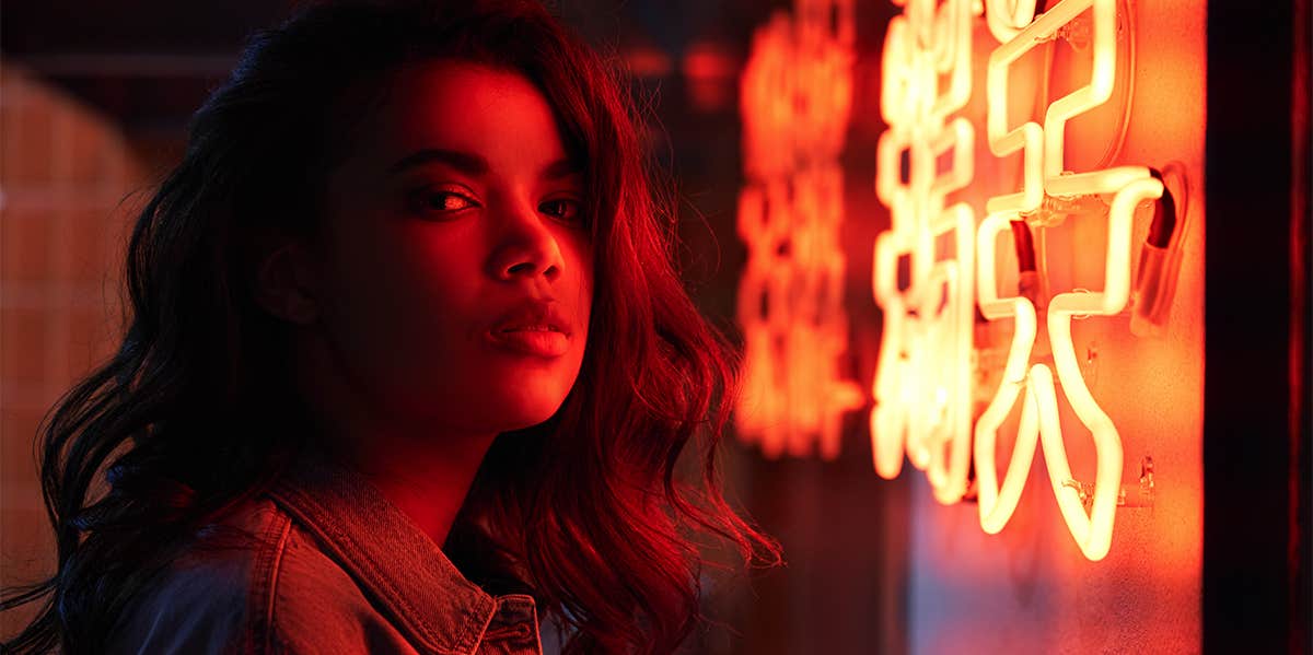 15 Toxic Things You Do Because You're Still In Love With Your Ex woman standing in neon light