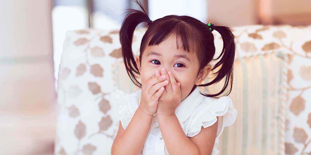 child covering her mouth