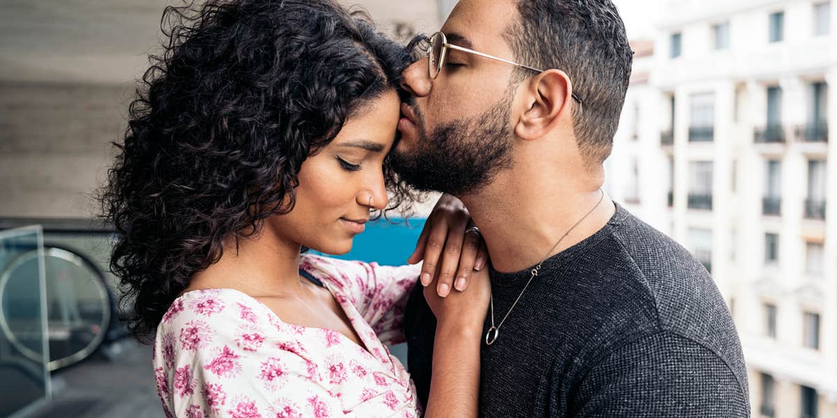 man kissing woman's forehead