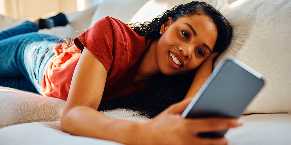 woman laying on couch texting