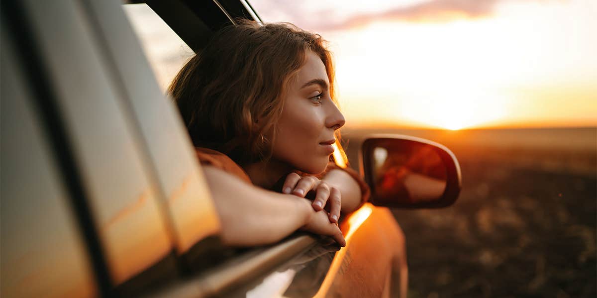 happy woman riding in car with head out of window