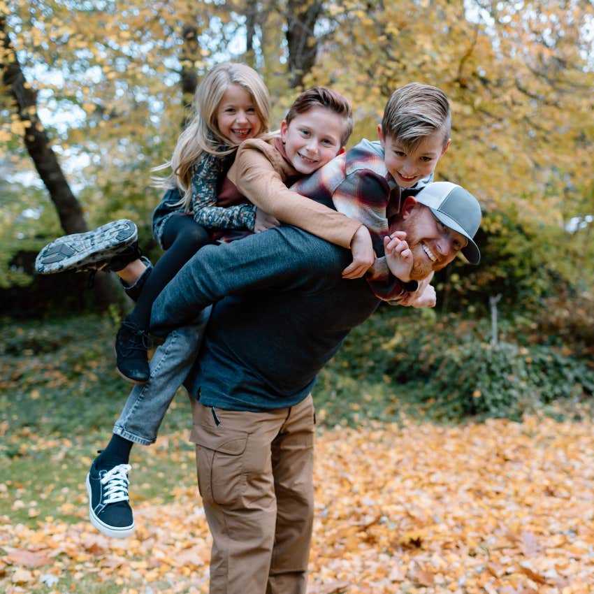 dad with his three kids on his back smiling