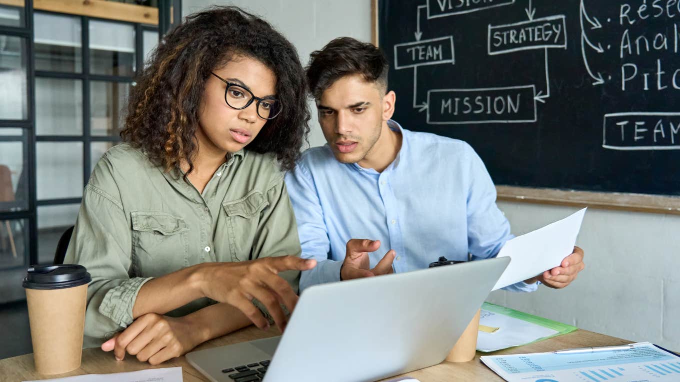 young coworkers discussing project together in modern office using laptop computer.