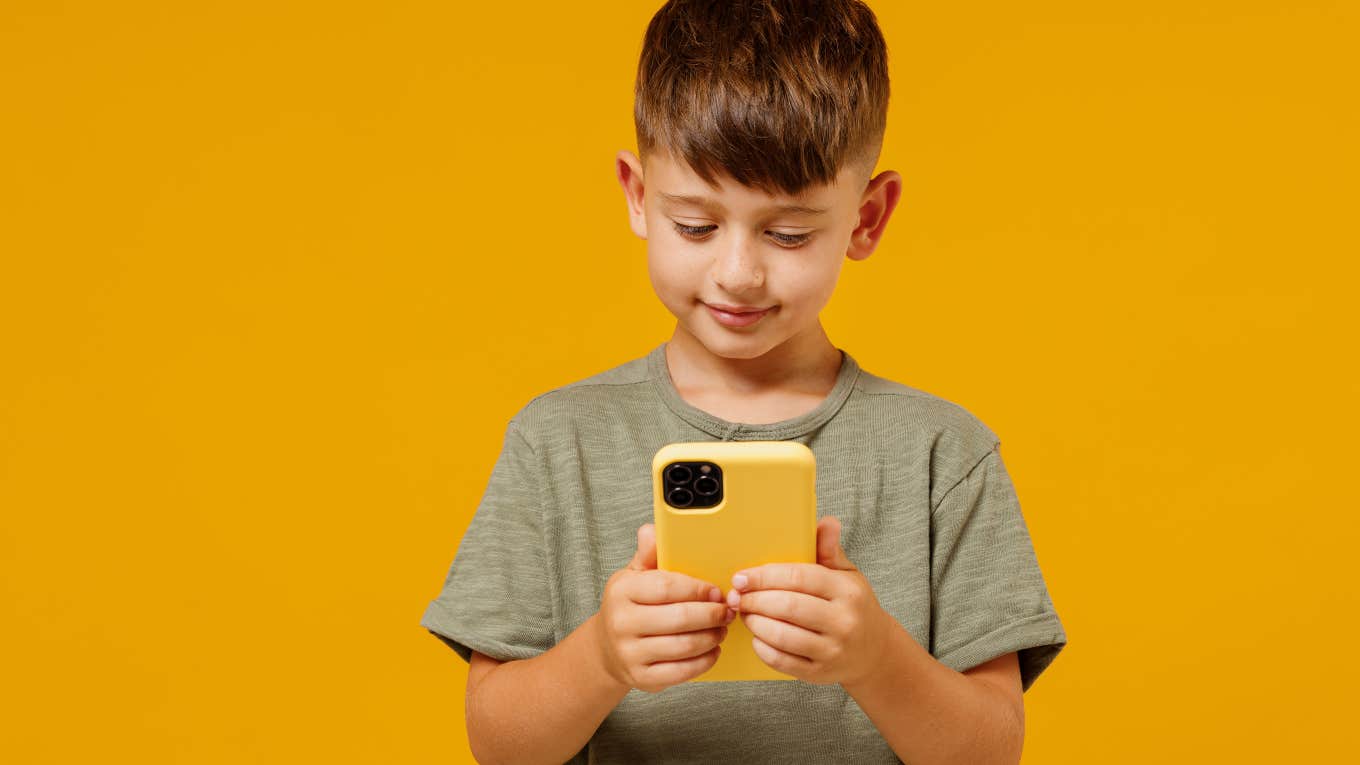 little boy on phone in front of orange background