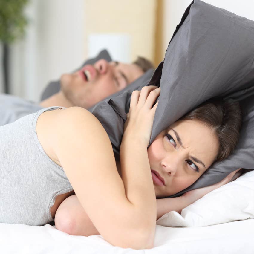 Man snoring while his wife is covering ears with the pillow