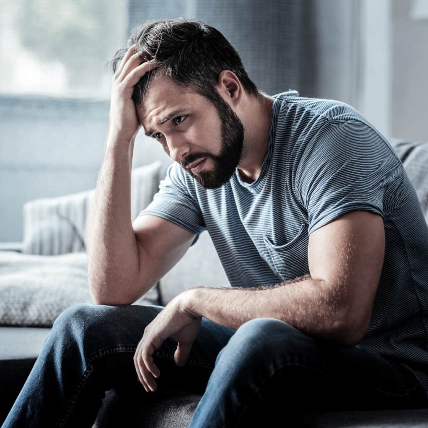  unhappy man sitting on the sofa and holding his forehead