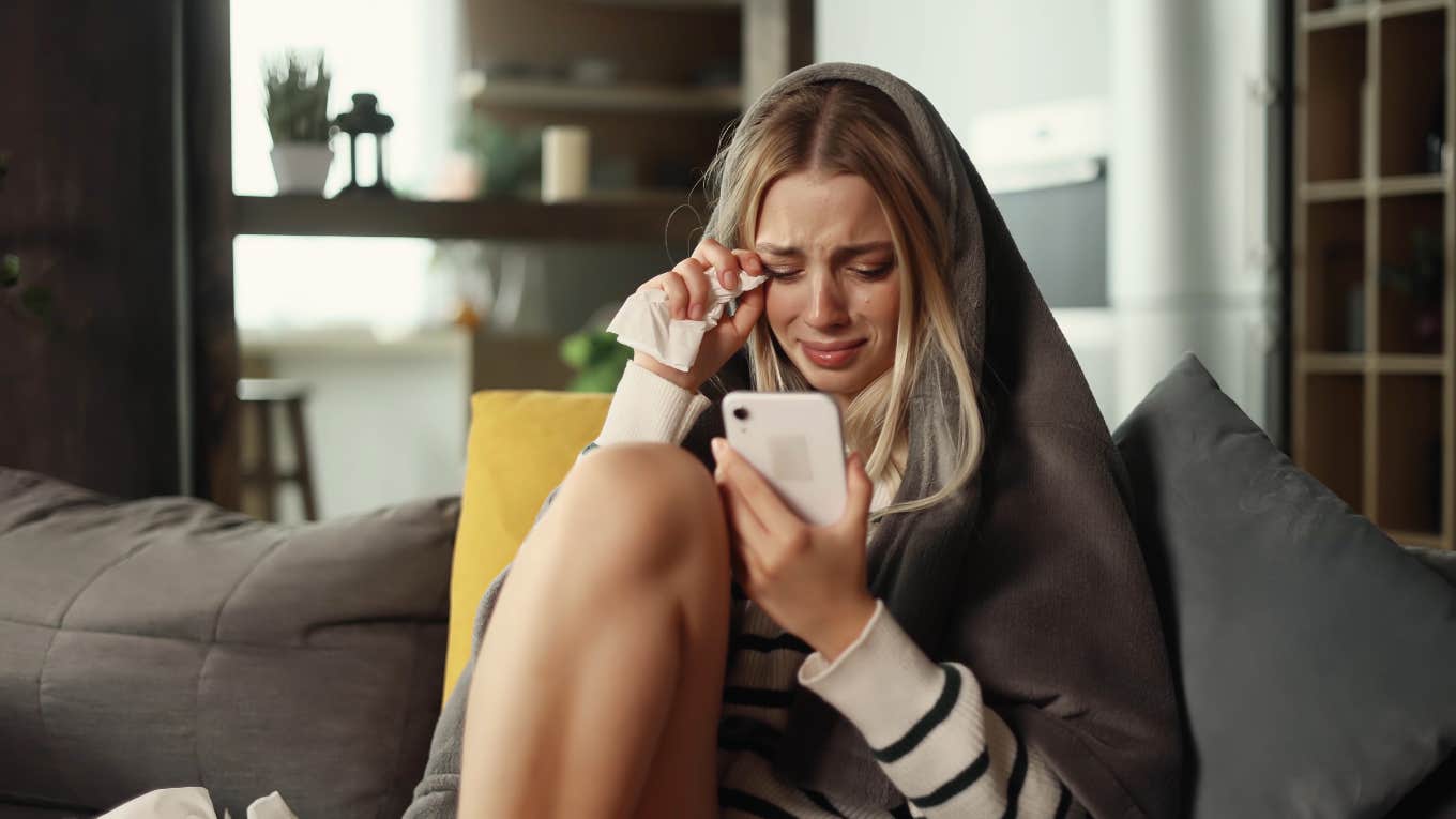 woman staring at phone while crying