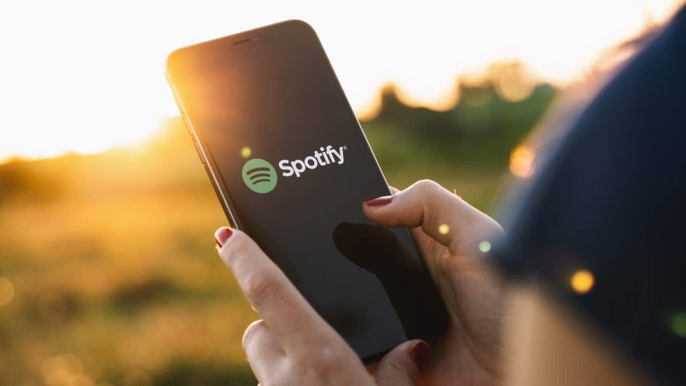 Spotify CEO Shocked That Laying Off Staff Presented A 'Challenge' woman holding phone with Spotify open