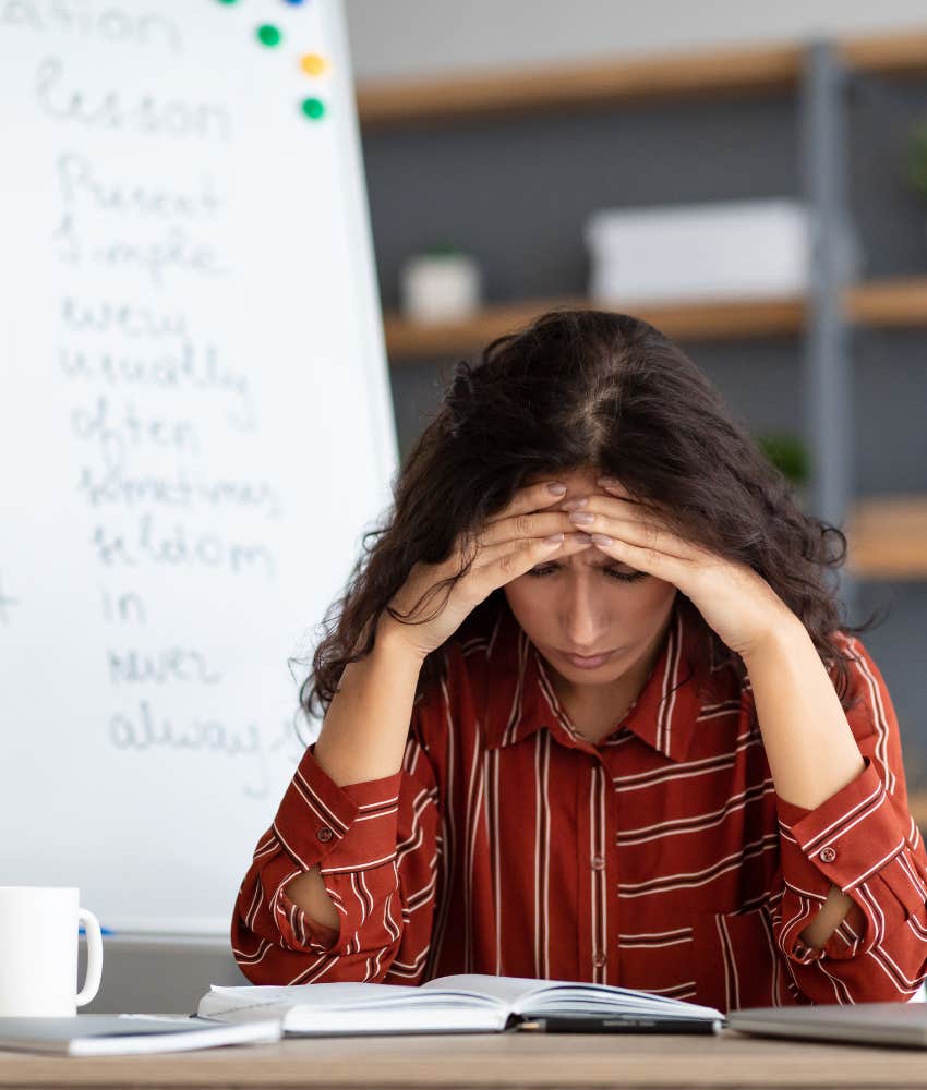 teacher with her head in her hands at desk